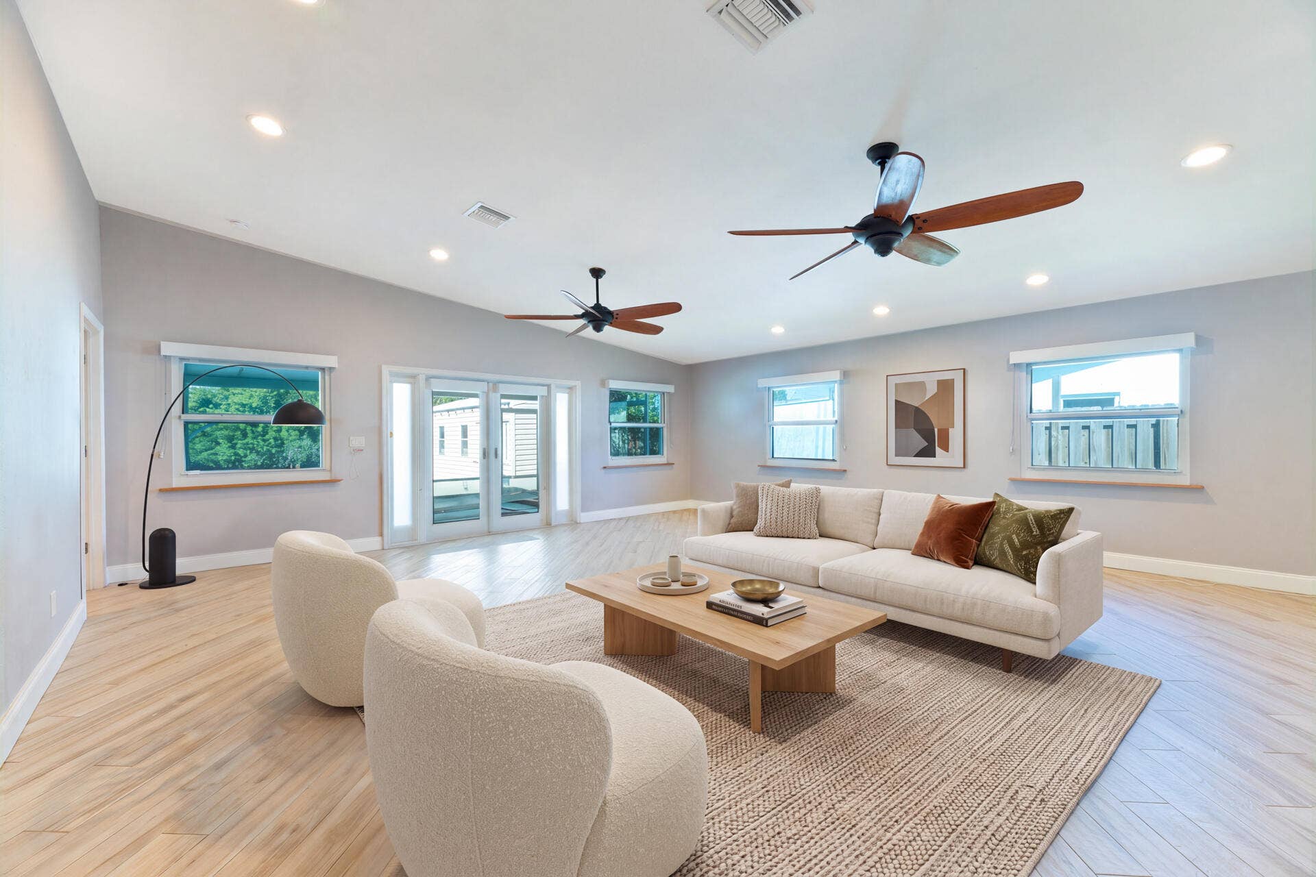 Open-concept room featuring ceramic plank flooring, recessed lighting, dual ceiling fans, and glass-paneled exterior doors