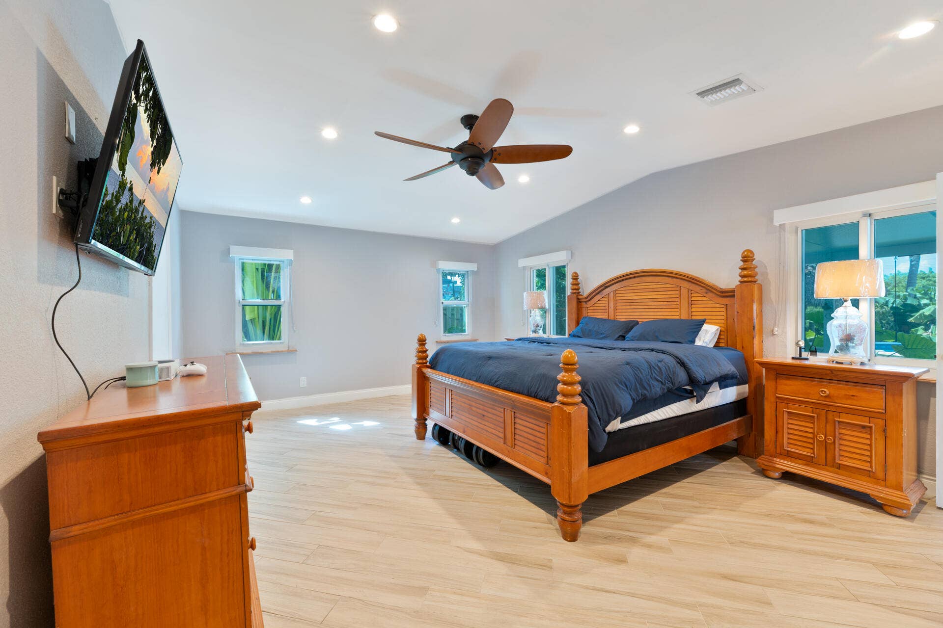 Vaulted ceilings featuring recessed lighting and a ceiling fan, complemented by ceramic plank flooring and multiple windows
