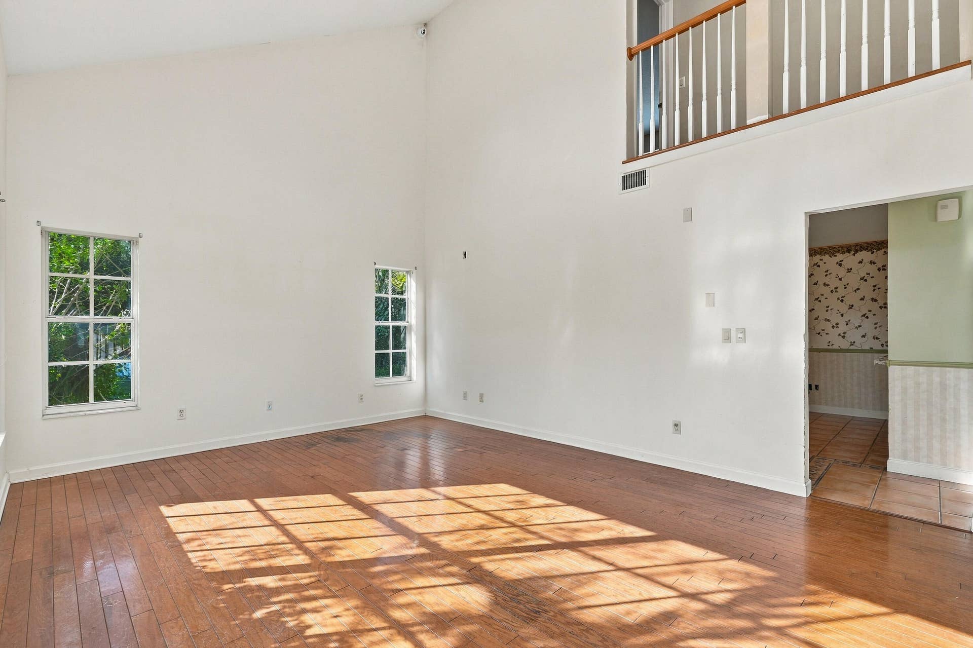 Vaulted ceilings, wood-finish flooring, multi-pane windows, and a railed mezzanine overlooking the open interior space