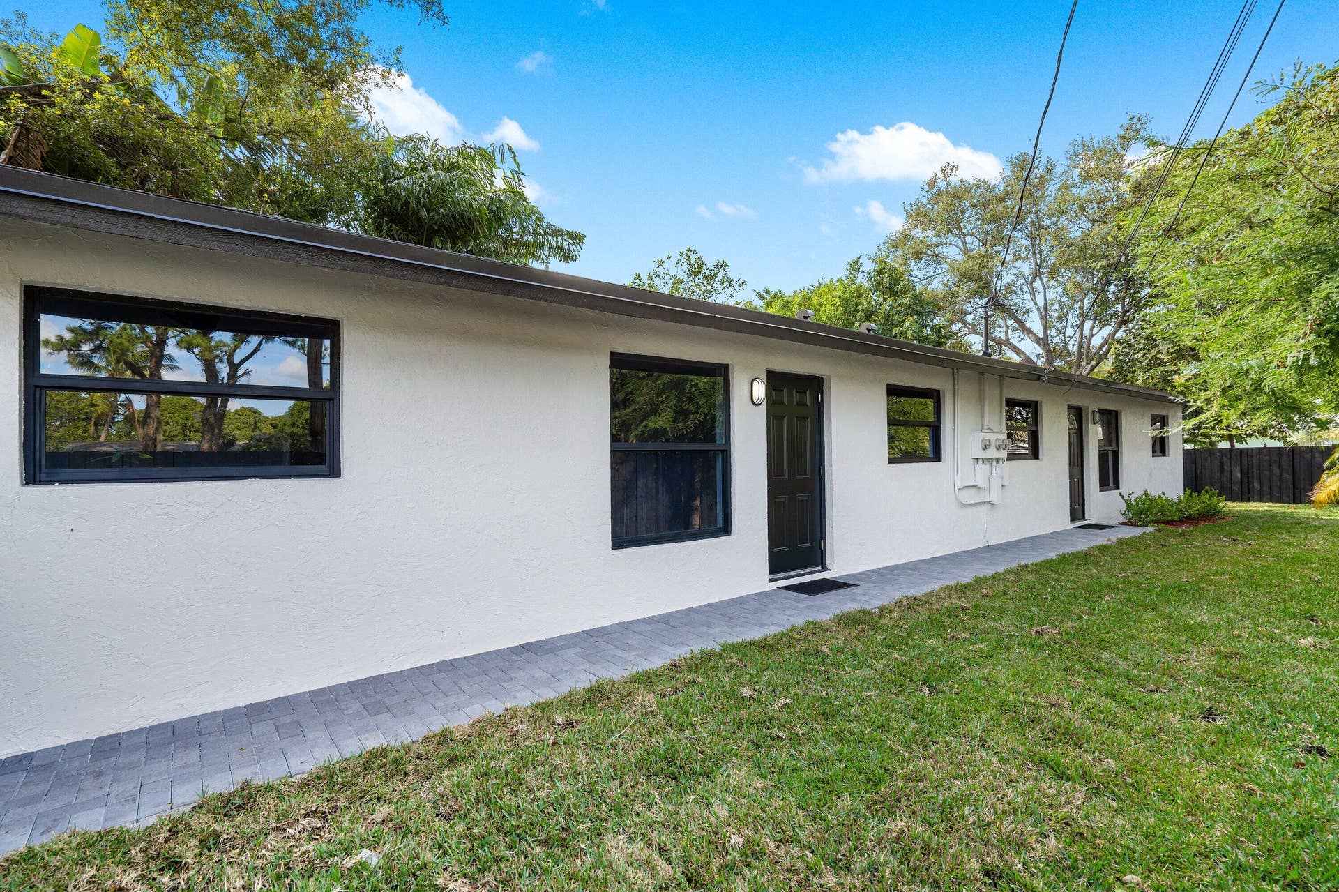 1211 NE 2nd Avenue, Fort Lauderdale, FL 33304 Stucco exterior featuring dark-framed windows, a paver walkway, and a manicured lawn