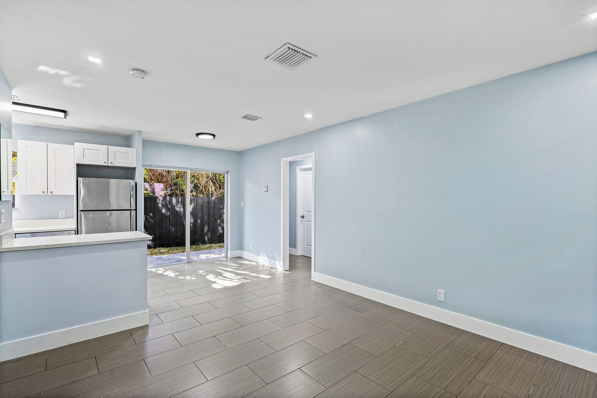 1211 NE 2nd Avenue, Fort Lauderdale, FL 33304 Open-concept space featuring ceramic tile flooring, kitchen with white cabinetry, stainless steel refrigerator, and glass sliding doors