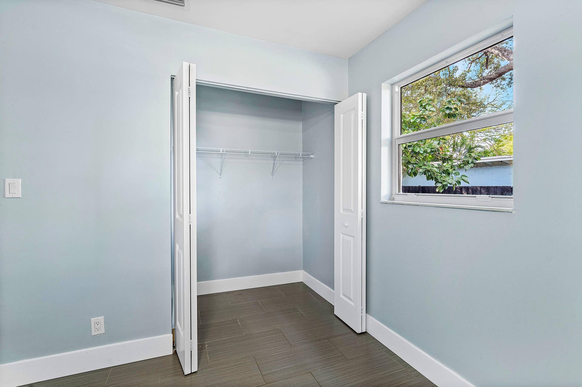 1211 NE 2nd Avenue, Fort Lauderdale, FL 33304 Neutral-toned room featuring a single-hung window, closet with bi-fold doors and wire shelving, and tile flooring