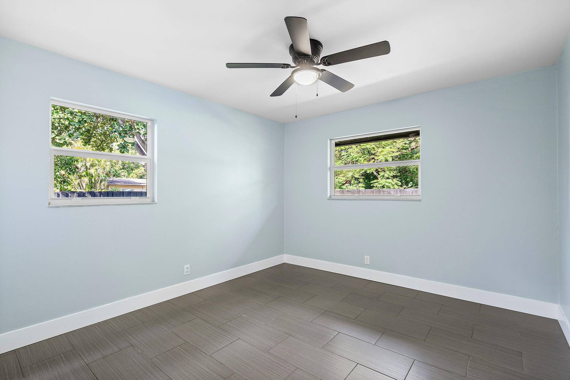 1211 NE 2nd Avenue, Fort Lauderdale, FL 33304 Interior space featuring neutral wall paint, dark tile flooring, dual windows, and a central ceiling fan with integrated lighting