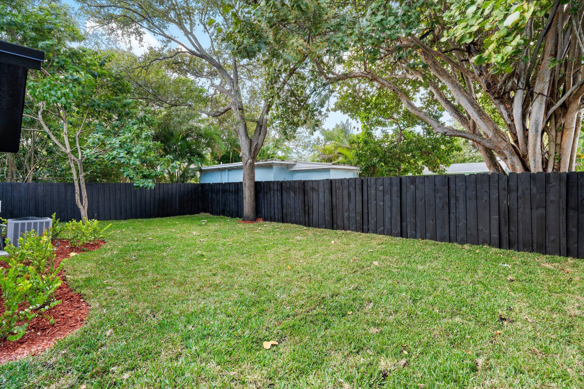 1211 NE 2nd Avenue, Fort Lauderdale, FL 33304 Private backyard featuring a manicured lawn, wood-finish privacy fencing, and mature trees