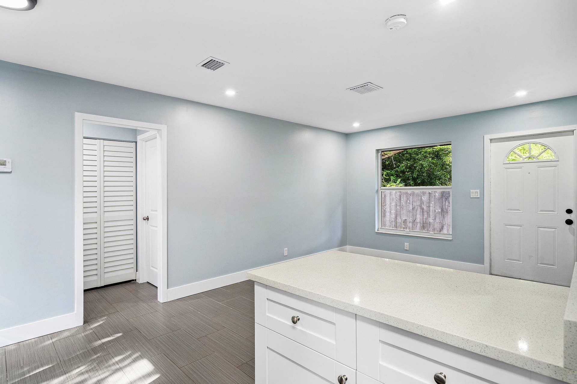 1211 NE 2nd Avenue, Fort Lauderdale, FL 33304 Interior featuring white built-in cabinetry with stone-finish countertops, grey tile flooring, louvered closet doors, and a paneled exterior door with glass insert