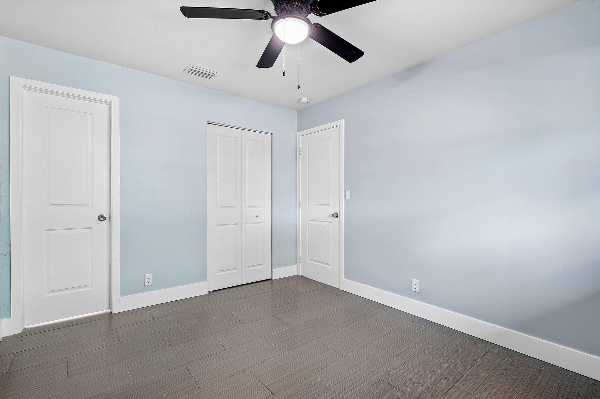 1211 NE 2nd Avenue, Fort Lauderdale, FL 33304 Interior space featuring wood-finish flooring, two-panel interior doors, a double-panel closet door, and a multi-blade ceiling fan with integrated lighting