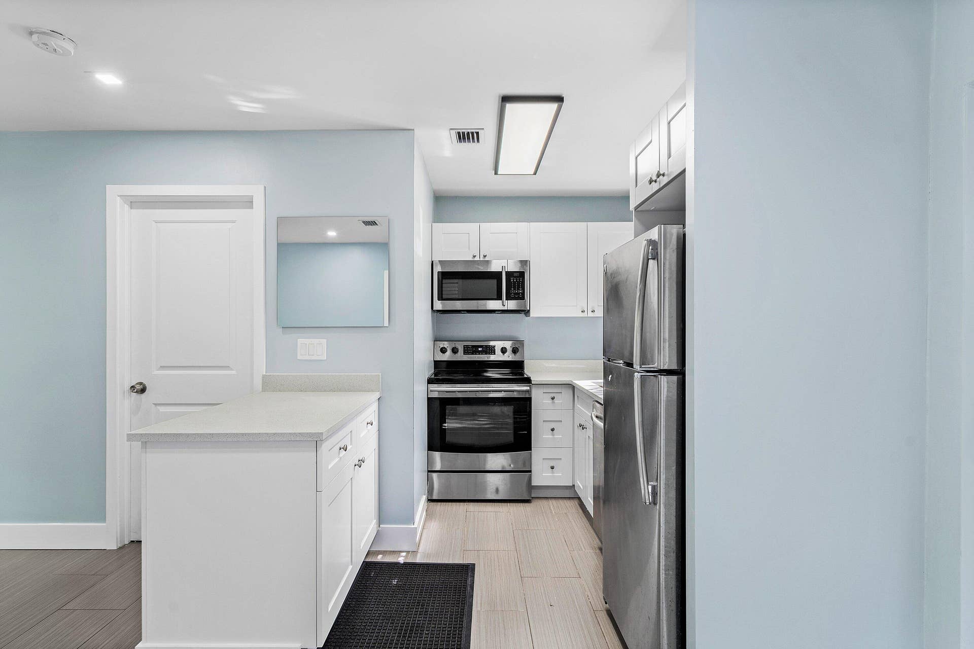 1211 NE 2nd Avenue, Fort Lauderdale, FL 33304 Kitchen featuring white cabinetry, solid-surface countertops, stainless steel appliances, and tile flooring