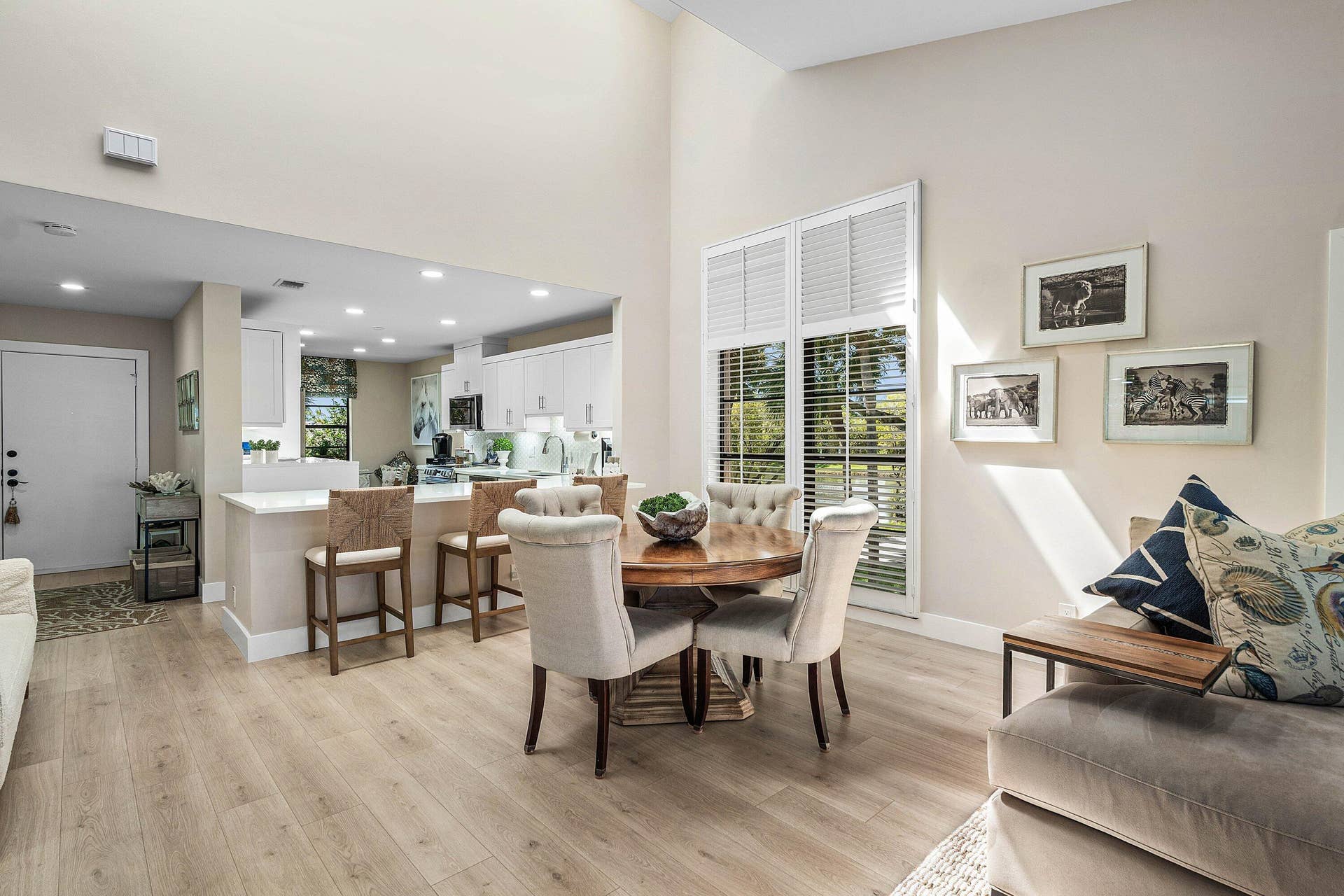 Open-concept space featuring vaulted ceilings, wood-finish flooring, recessed lighting, and a kitchen island with stone-finish countertops
