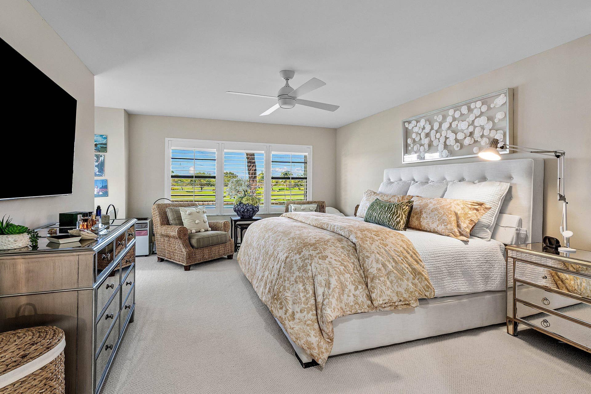 Neutral-toned carpeted flooring, white ceiling fan with integrated lighting, and three-pane window configuration featuring plantation-style shutters