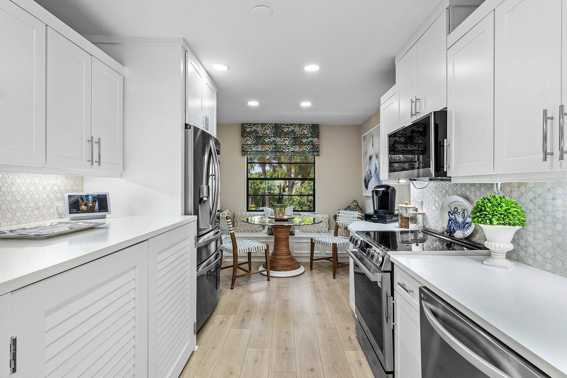 Kitchen featuring white shaker-style cabinetry, solid-surface countertops, patterned tile backsplash, stainless steel appliances, and wood-finish flooring