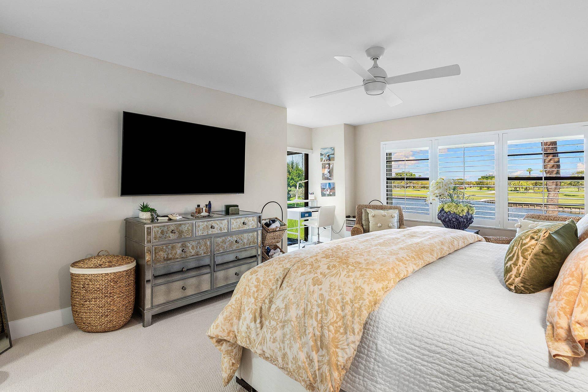 Neutral-toned room featuring a central ceiling fan, expansive triple-pane windows with horizontal blinds, and carpeting