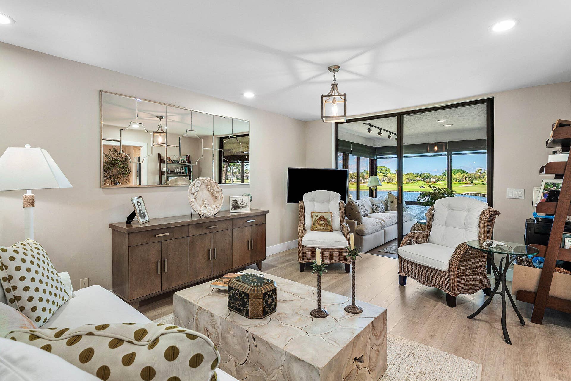 Living area featuring wood-finish flooring, recessed lighting, a large-scale wall mirror, and sliding glass doors opening to a screened enclosure