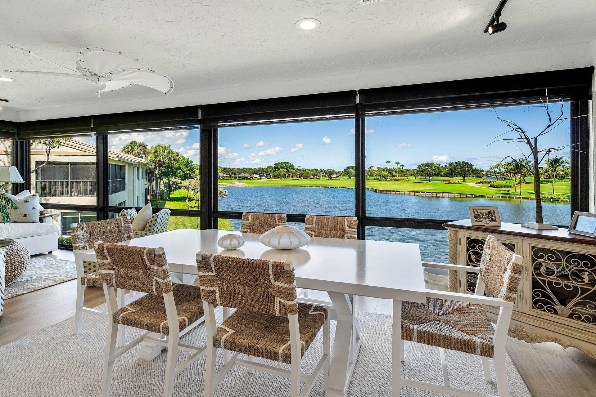 Floor-to-ceiling windows with black framing, wood-finish flooring, recessed lighting, and water backdrop