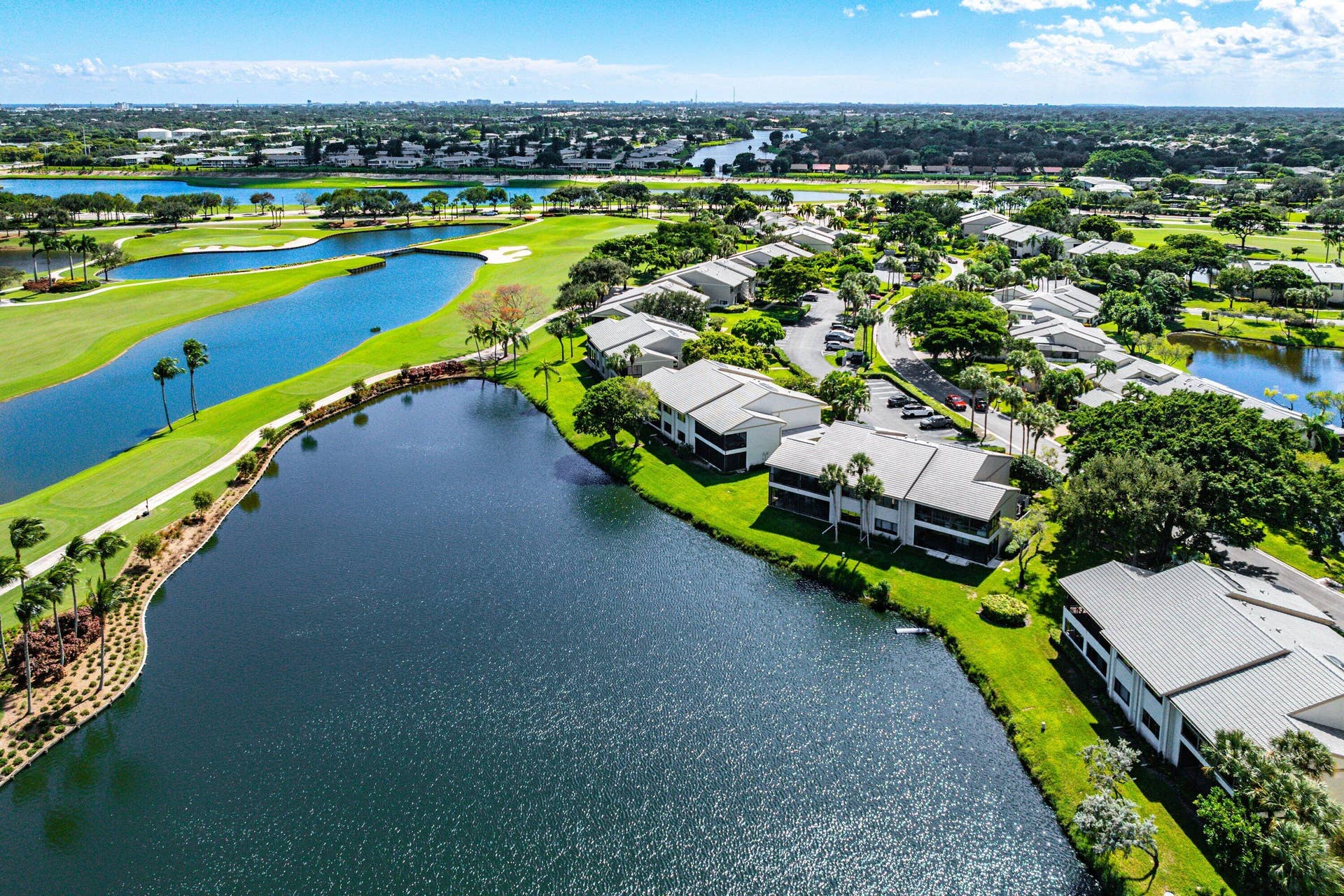 Aerial perspective of waterfront properties featuring manicured landscaping, mature trees, and proximity to golf course fairways