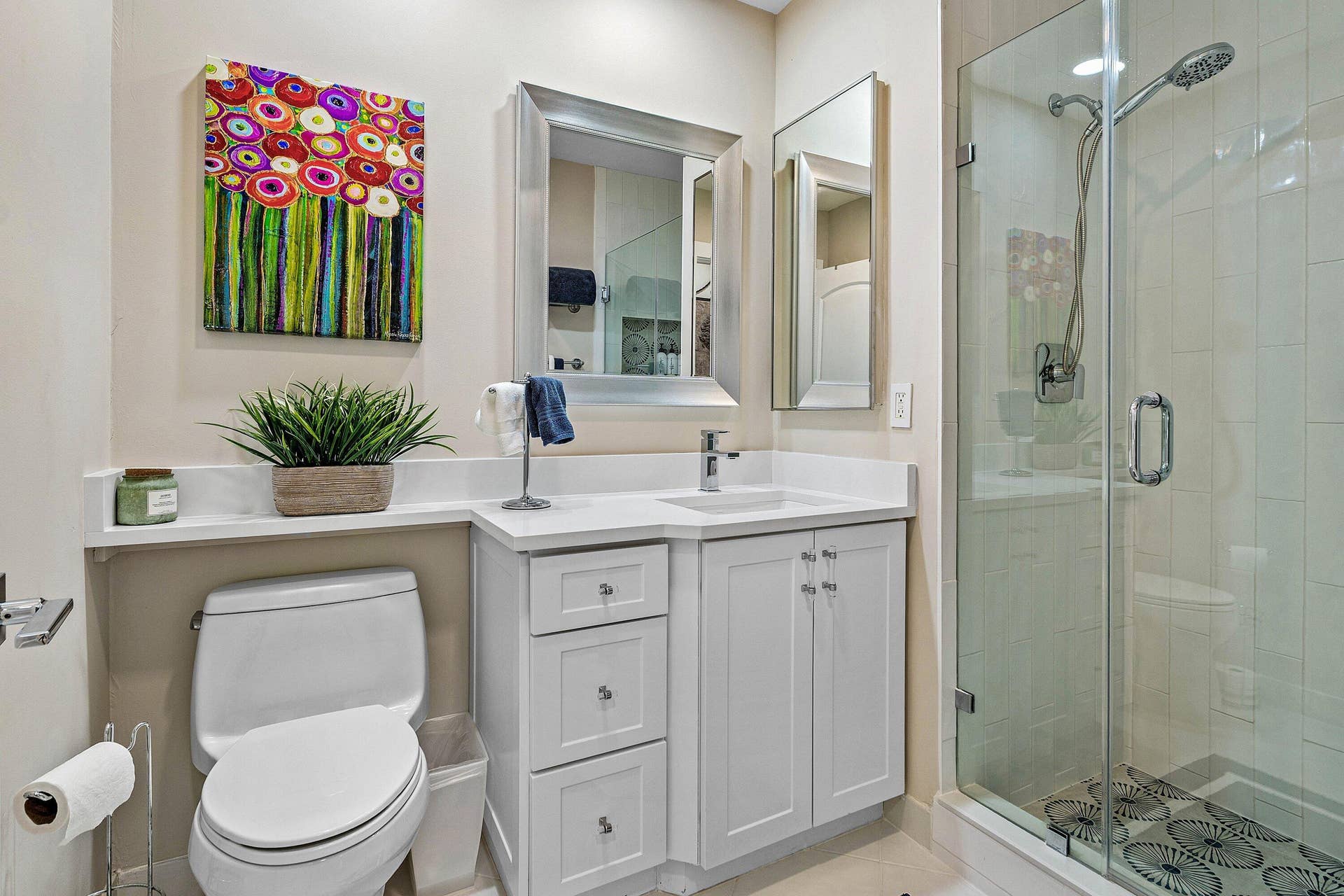 Bathroom featuring a white vanity cabinet with quartz countertops, an undermount sink, a glass-enclosed shower with tiled walls, and a wall-mounted medicine cabinet