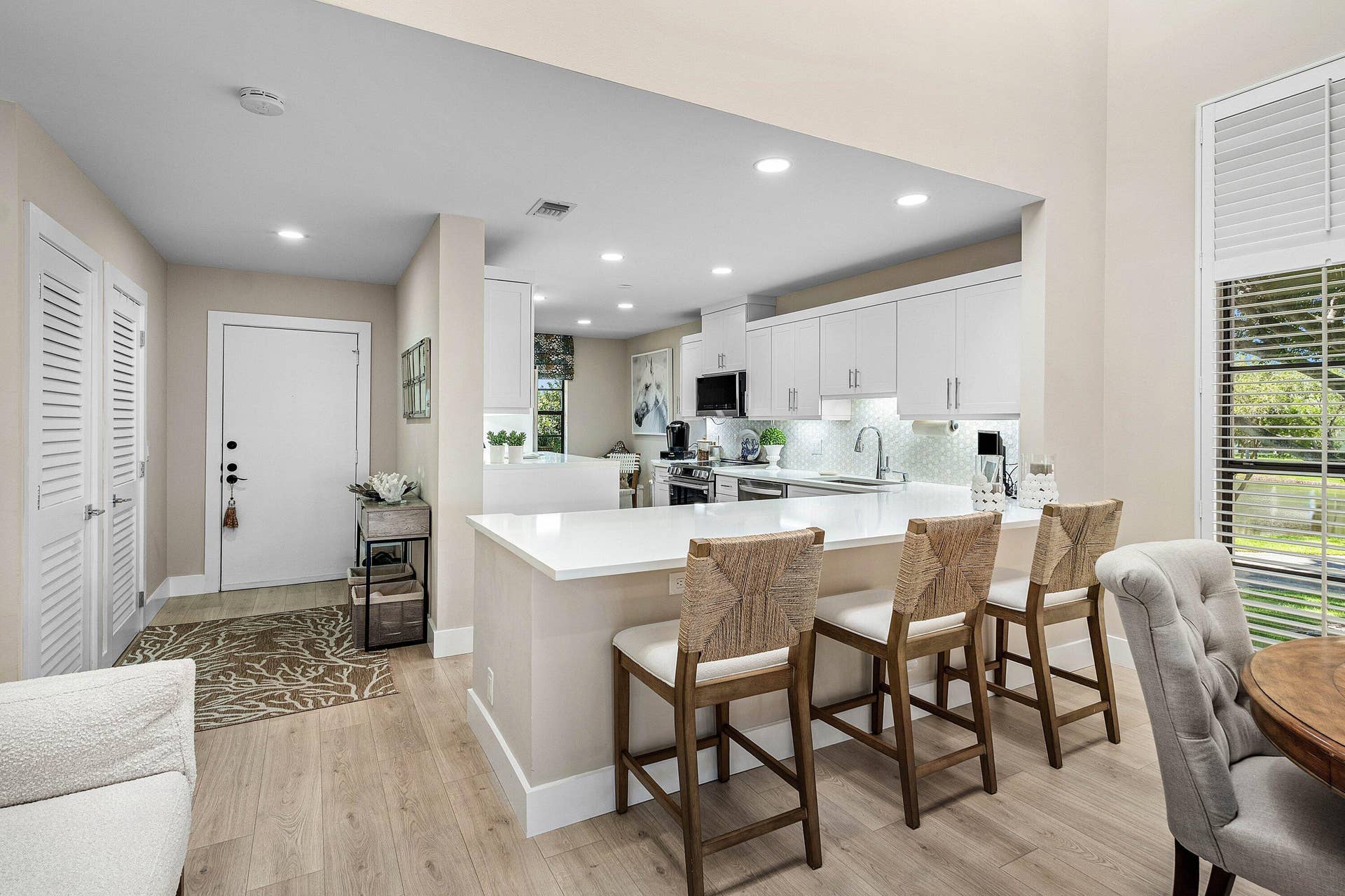 Kitchen featuring white cabinetry, quartz countertops, a breakfast bar, recessed lighting, and wood-finish flooring