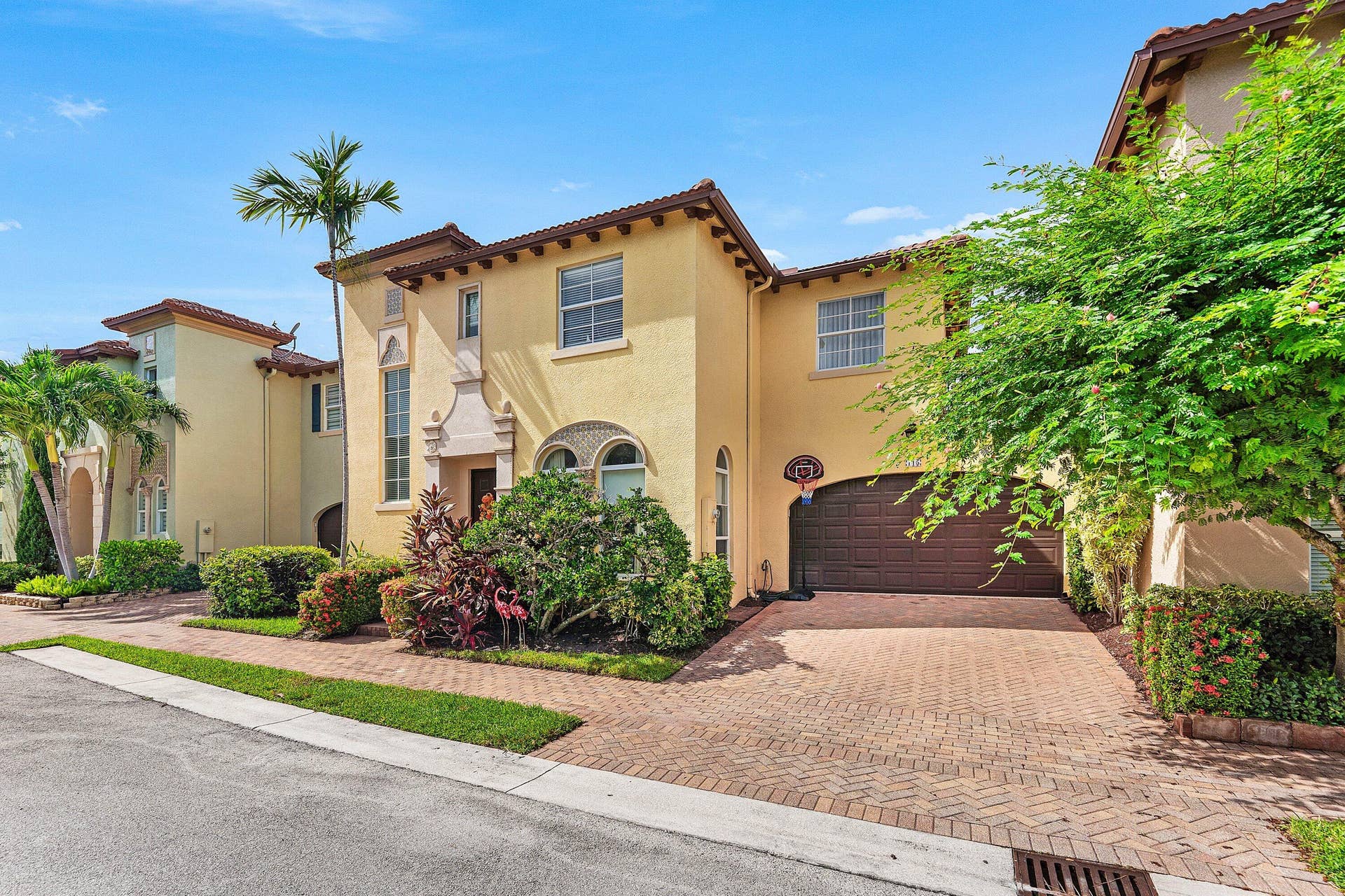 115 VIA POINCIANA Lane, Boca Raton, FL 33487 Inviting exterior view highlighting the well-maintained landscaping, arched details, and private two-car garage