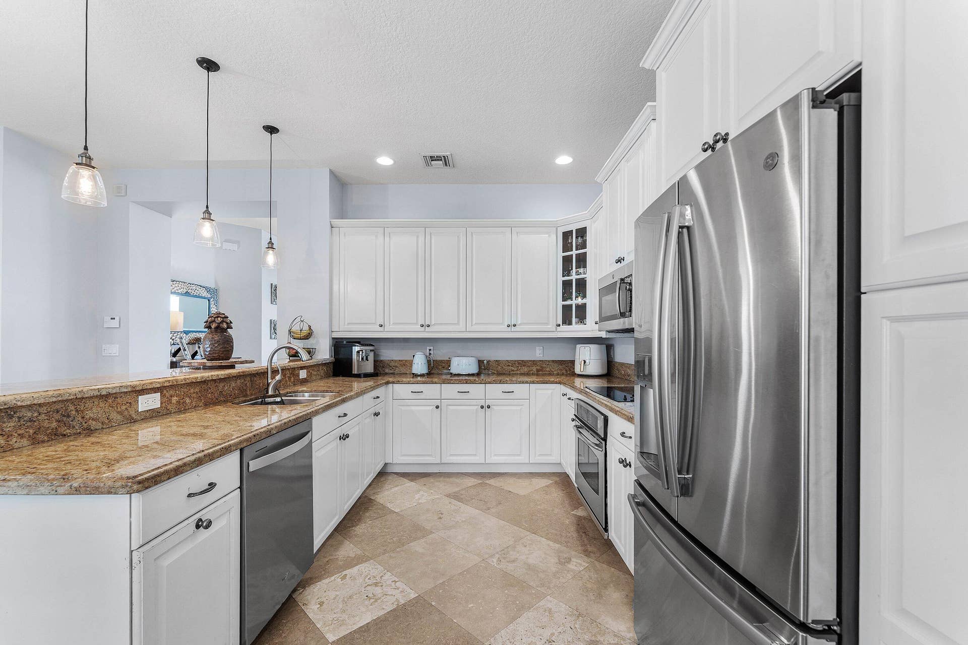 115 VIA POINCIANA Lane, Boca Raton, FL 33487 Spacious gourmet kitchen featuring white cabinetry, stainless steel appliances, granite countertops, a large center island, and abundant natural light.