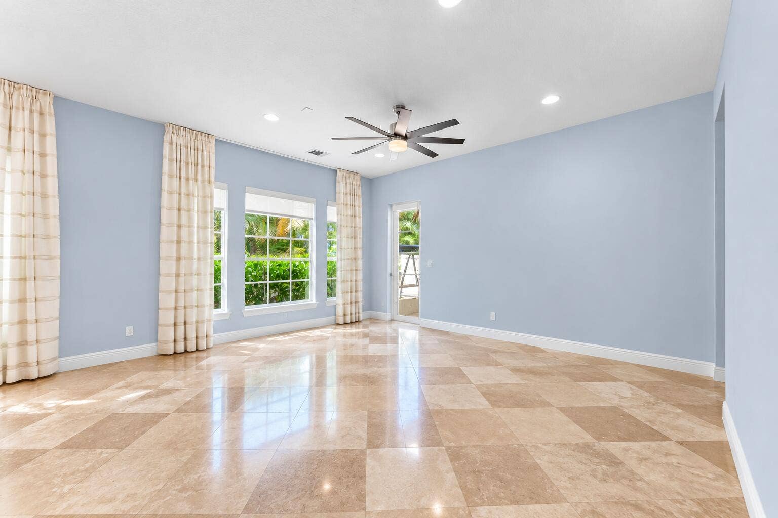 115 VIA POINCIANA Lane, Boca Raton, FL 33487 Bright, spacious family room featuring polished tile floors, abundant natural light, recessed lighting, and seamless access to the outdoor living space.