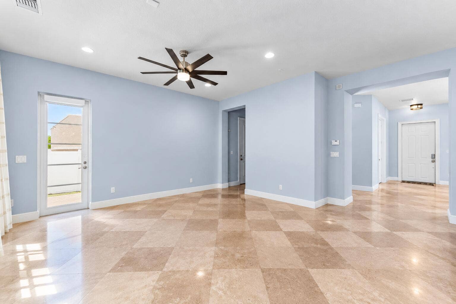 115 VIA POINCIANA Lane, Boca Raton, FL 33487 Open-concept family room with high ceilings, sleek modern ceiling fan, polished tile flooring, and plenty of natural light creating an inviting living space.