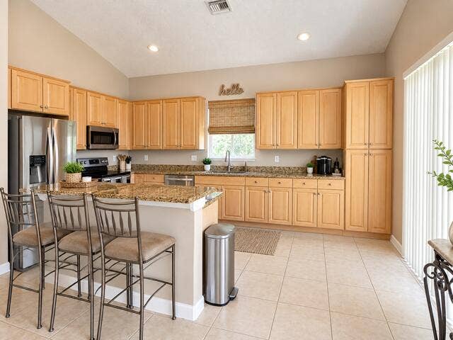 12142 Colony Preserve Drive, Boynton Beach, FL 33436 Spacious kitchen equipped with warm wood cabinetry, granite counter space, full-height pantry, stainless steel appliances, and multi-seat breakfast bar.