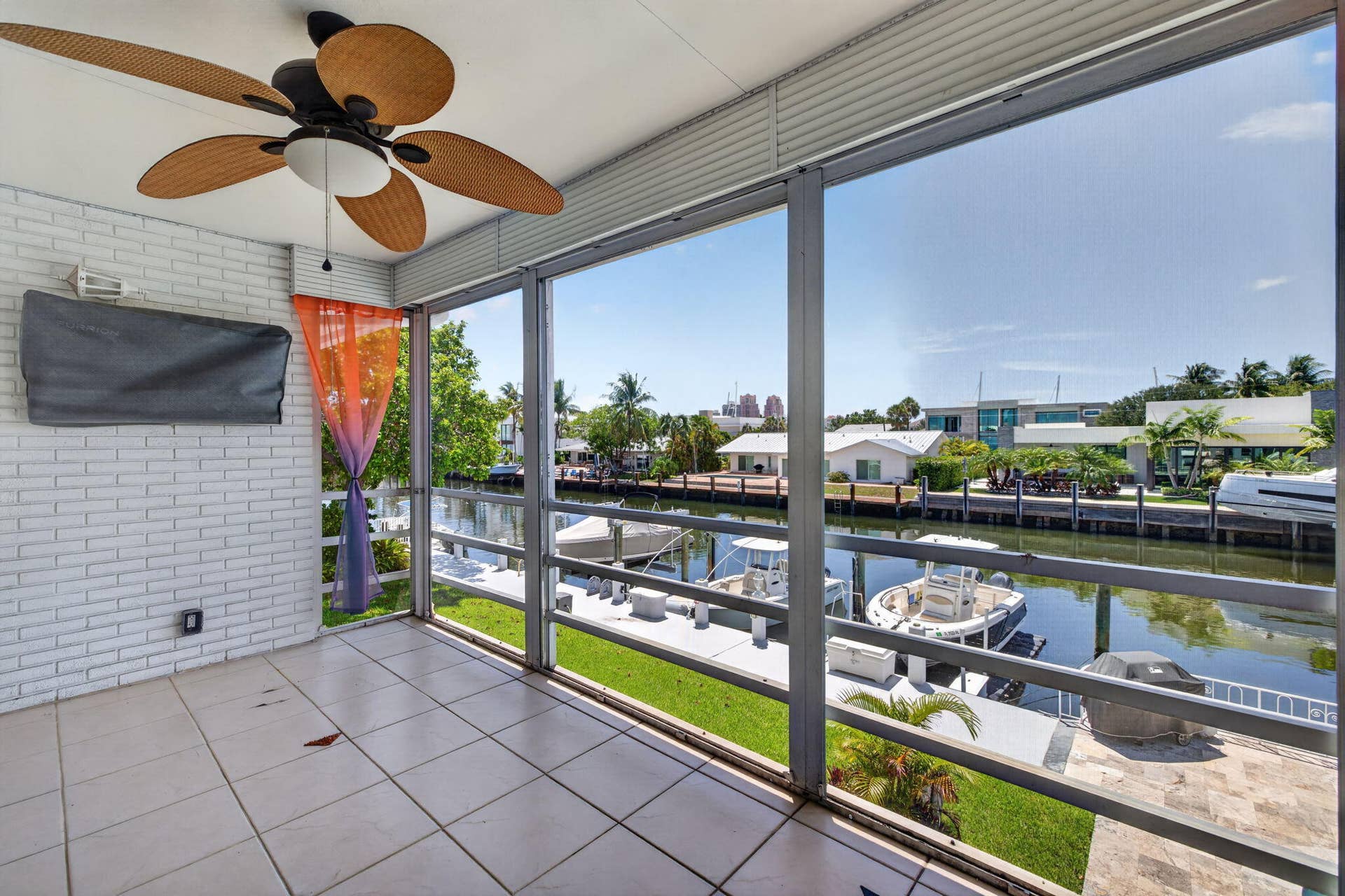 2820 NE 30TH Street, #9, Fort Lauderdale, FL 33306 Screened outdoor area with tile flooring, white brick wall, and a woven ceiling fan
