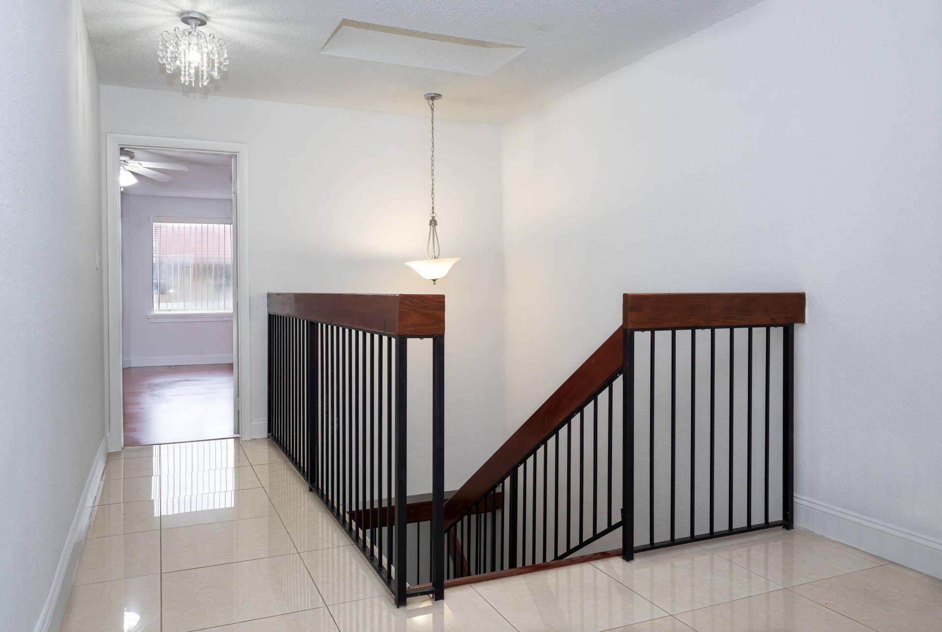 9981 W ATLANTIC Boulevard, #9981, Coral Springs, FL 33071 Elegant staircase with dark wood railings and spindle detailing, polished tile flooring, and pendant lighting