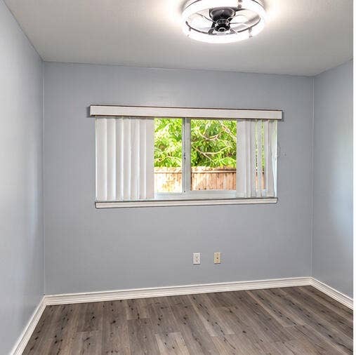 3601 SW 54th Avenue, West Park, FL 33023 Room featuring neutral wall paint, wood-finish flooring, a ceiling-mounted light fixture, and a window with vertical blinds