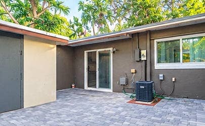 3601 SW 54th Avenue, West Park, FL 33023 Paved patio featuring stone-finish pavers, sliding glass door, and exterior wall-mounted lighting