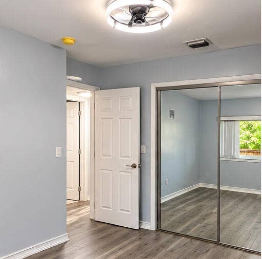3601 SW 54th Avenue, West Park, FL 33023 Wood-finish flooring, mirrored sliding closet doors, and modern integrated LED ceiling fan fixture
