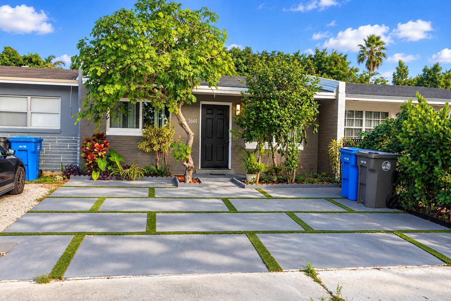 3601 SW 54th Avenue, West Park, FL 33023 Grey brick exterior featuring a concrete paver driveway with integrated turf ribbons and mature landscaping
