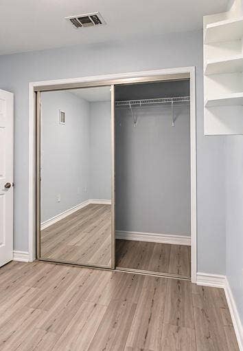 3601 SW 54th Avenue, West Park, FL 33023 Sliding mirrored closet doors, wood-finish flooring, and built-in wall shelving