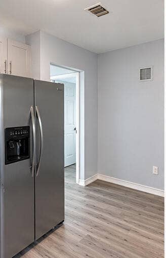 3601 SW 54th Avenue, West Park, FL 33023 Stainless steel side-by-side refrigerator, white shaker-style cabinetry, and wood-finish flooring