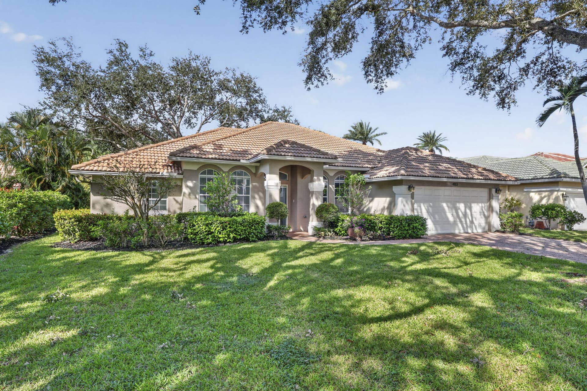 483 OTTER Lane N, Jupiter, FL 33458 Stucco exterior featuring a clay tile roof, arched windows, covered entryway with decorative columns, and an attached multi-car garage