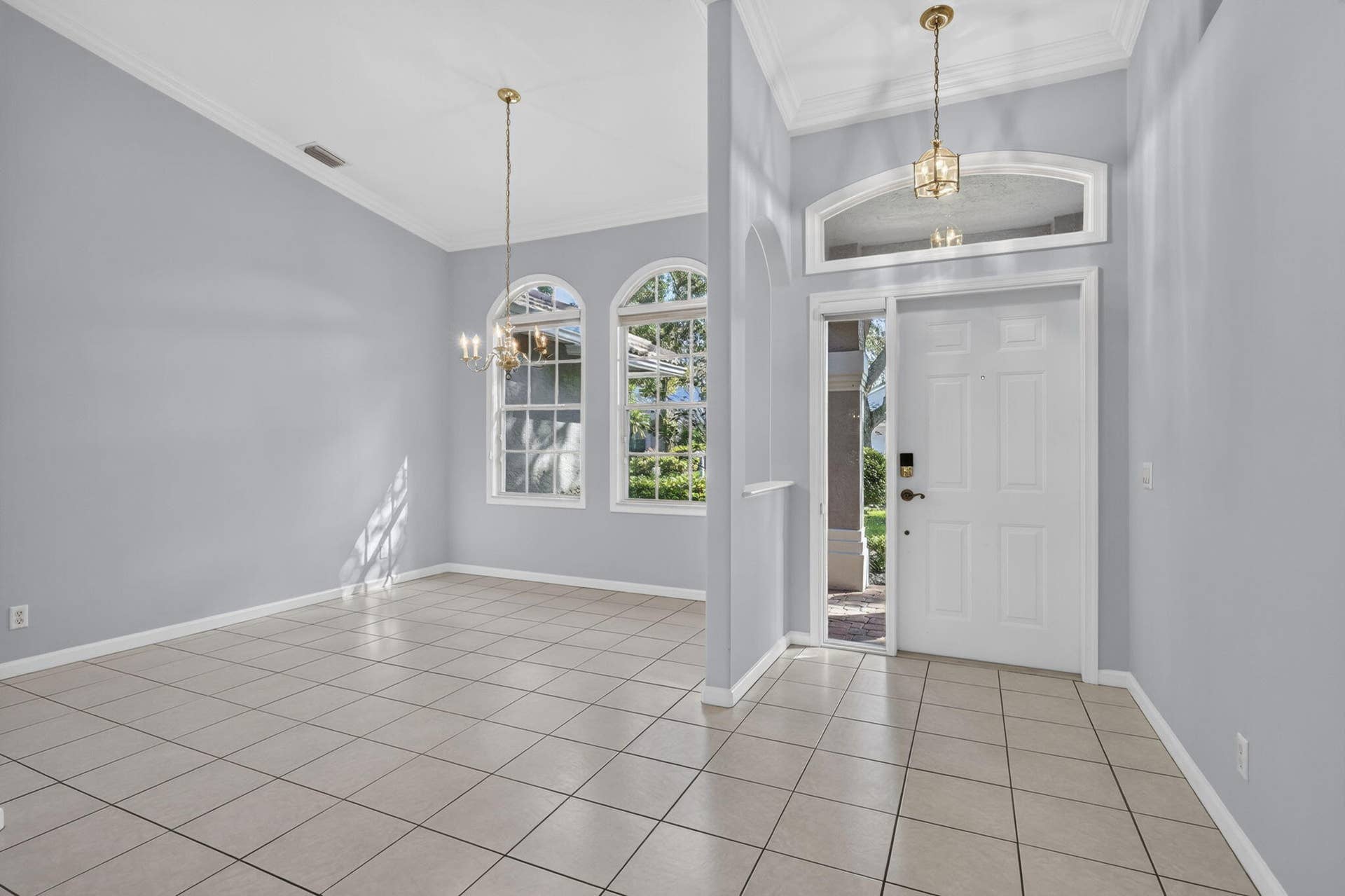 483 OTTER Lane N, Jupiter, FL 33458 Entrance foyer and surrounding area featuring vaulted ceilings, arched windows, tile flooring, and decorative hanging light fixtures