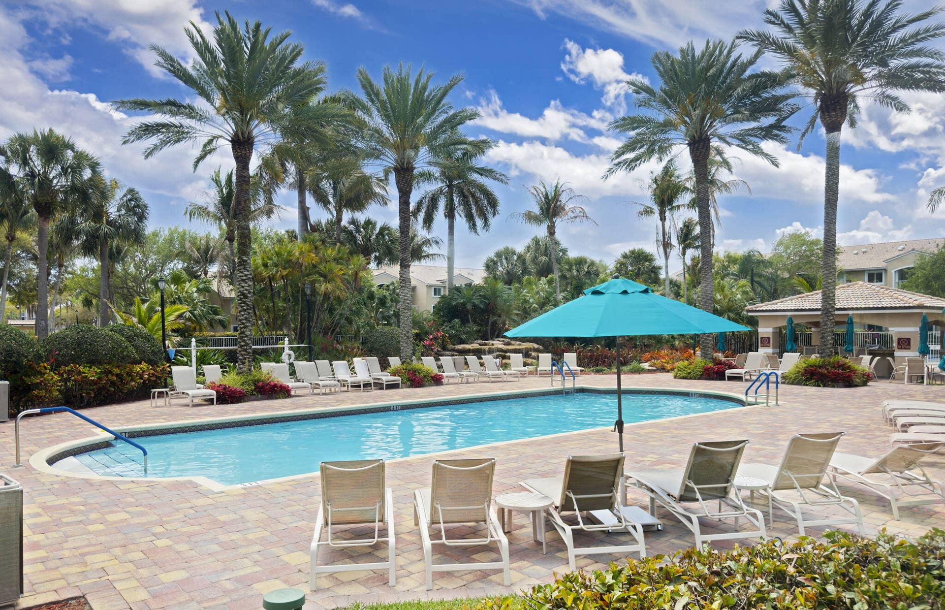 Swimming pool with paver decking, established palm trees, and a covered pavilion