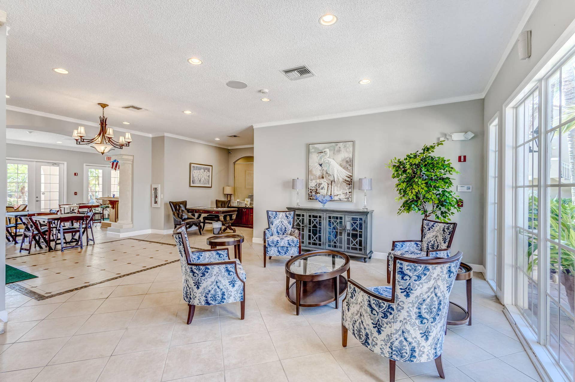 Open-concept common area featuring large format tile flooring, recessed lighting, a decorative multi-arm chandelier, and floor-to-ceiling windows