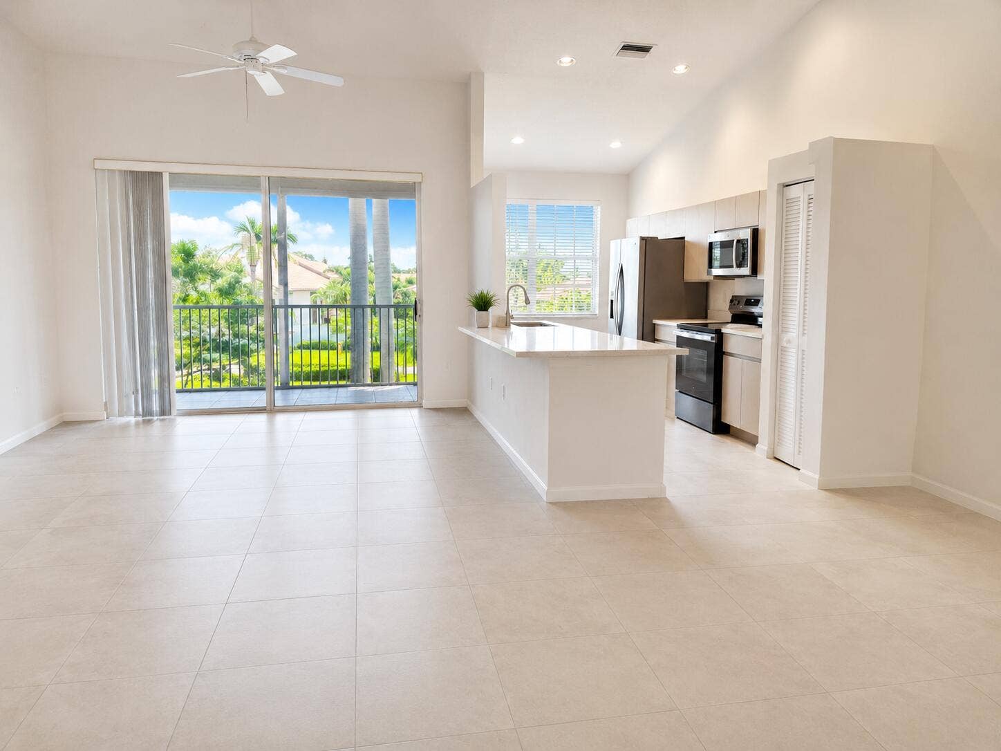 6560 VILLA SONRISA Drive, #1321, Boca Raton, FL 33433 Open floor plan featuring large-format tile flooring, a kitchen island with stone-finish countertops, vaulted ceilings, and a sliding glass door opening to a private balcony