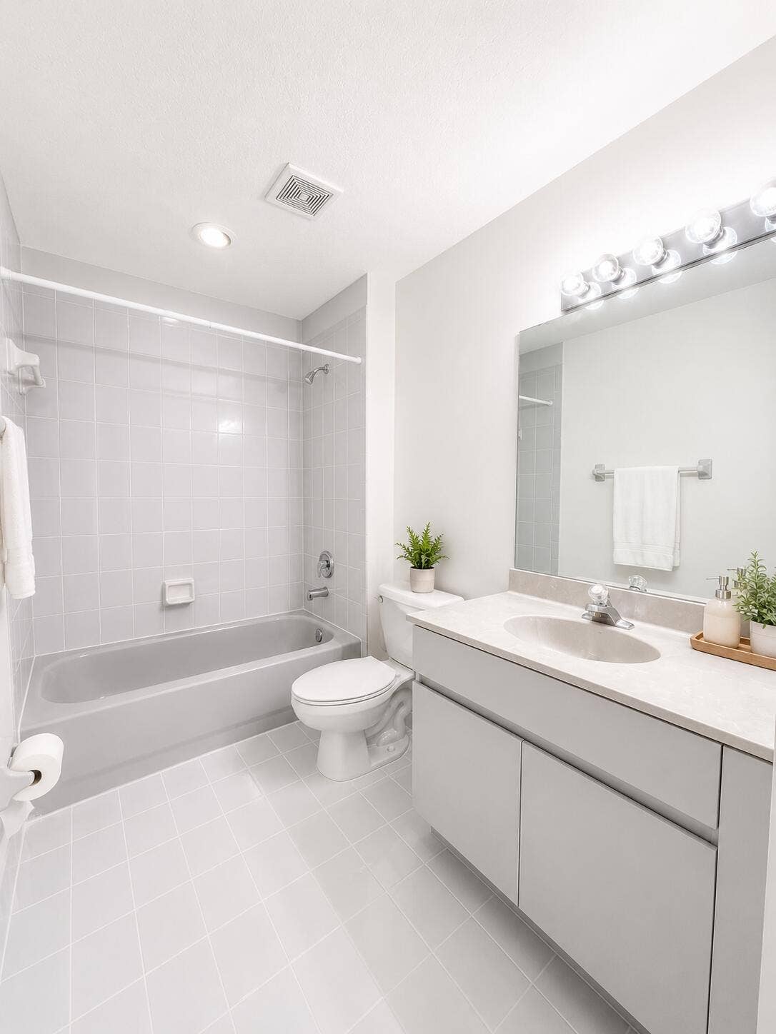 6560 VILLA SONRISA Drive, #1321, Boca Raton, FL 33433 Bathroom featuring a vanity with a light-toned countertop, integrated basin, wall-to-wall mirror, tiled bathtub surround, and light-toned tile flooring