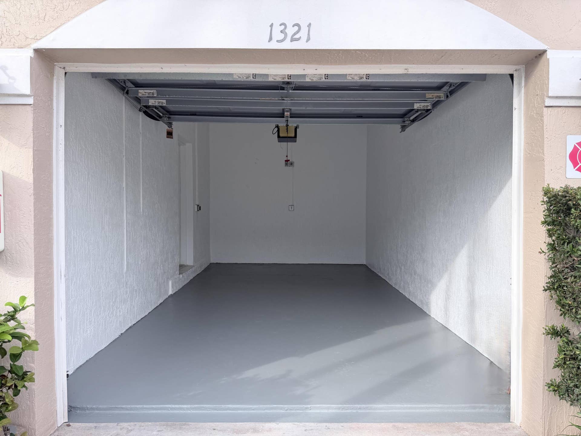 6560 VILLA SONRISA Drive, #1321, Boca Raton, FL 33433 Attached garage featuring smooth white walls, an automated overhead door opener