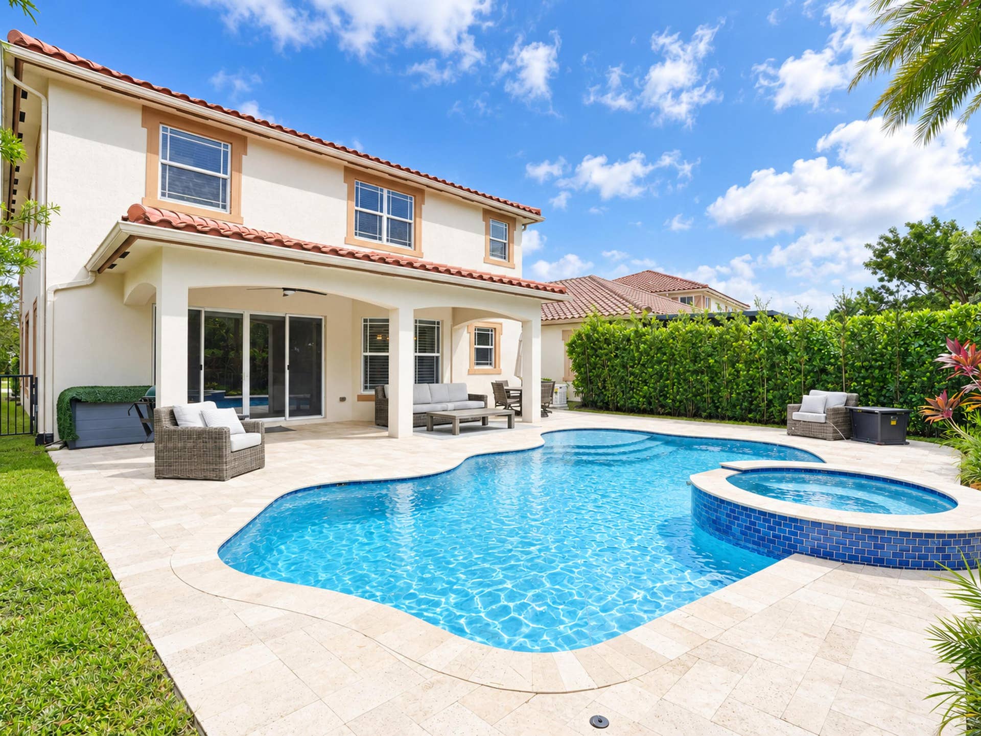8601 Waterside Court, Parkland, FL 33076 Stucco exterior with a tile roof, featuring a covered patio, stone paver pool deck, free-form swimming pool, and an integrated tiled spa