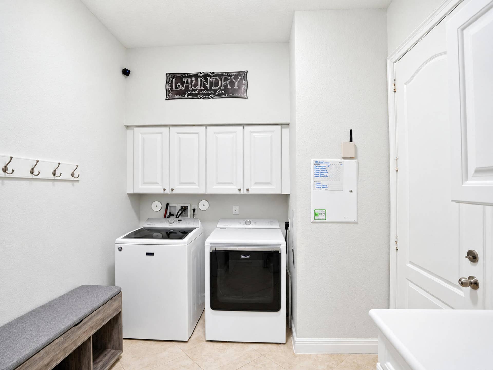 8601 Waterside Court, Parkland, FL 33076 Laundry area featuring upper white cabinetry, wall-mounted coat hooks, and neutral tile flooring