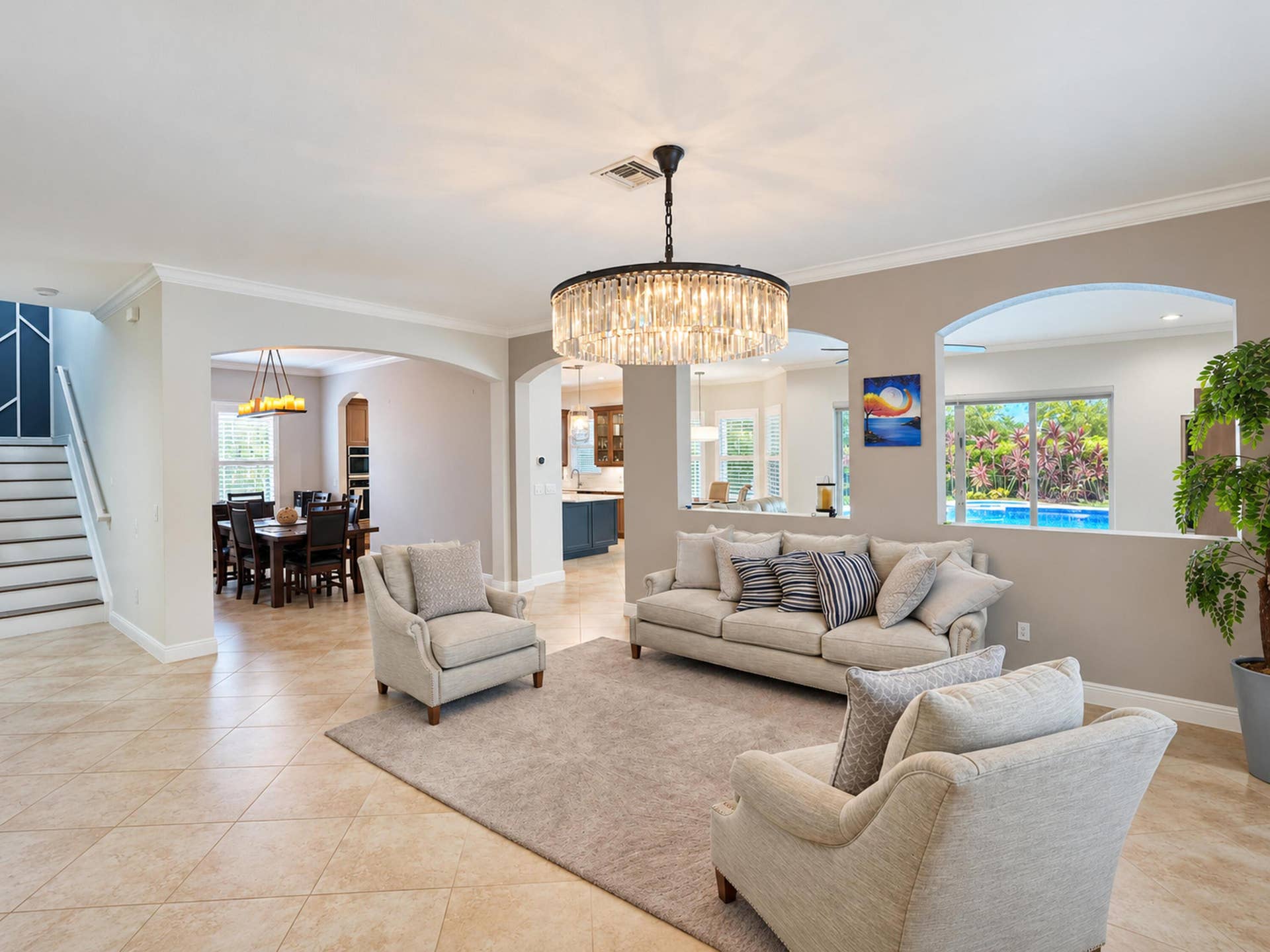 8601 Waterside Court, Parkland, FL 33076 Open floor plan featuring tile flooring, arched wall openings, crown molding, and a tiered crystal chandelier