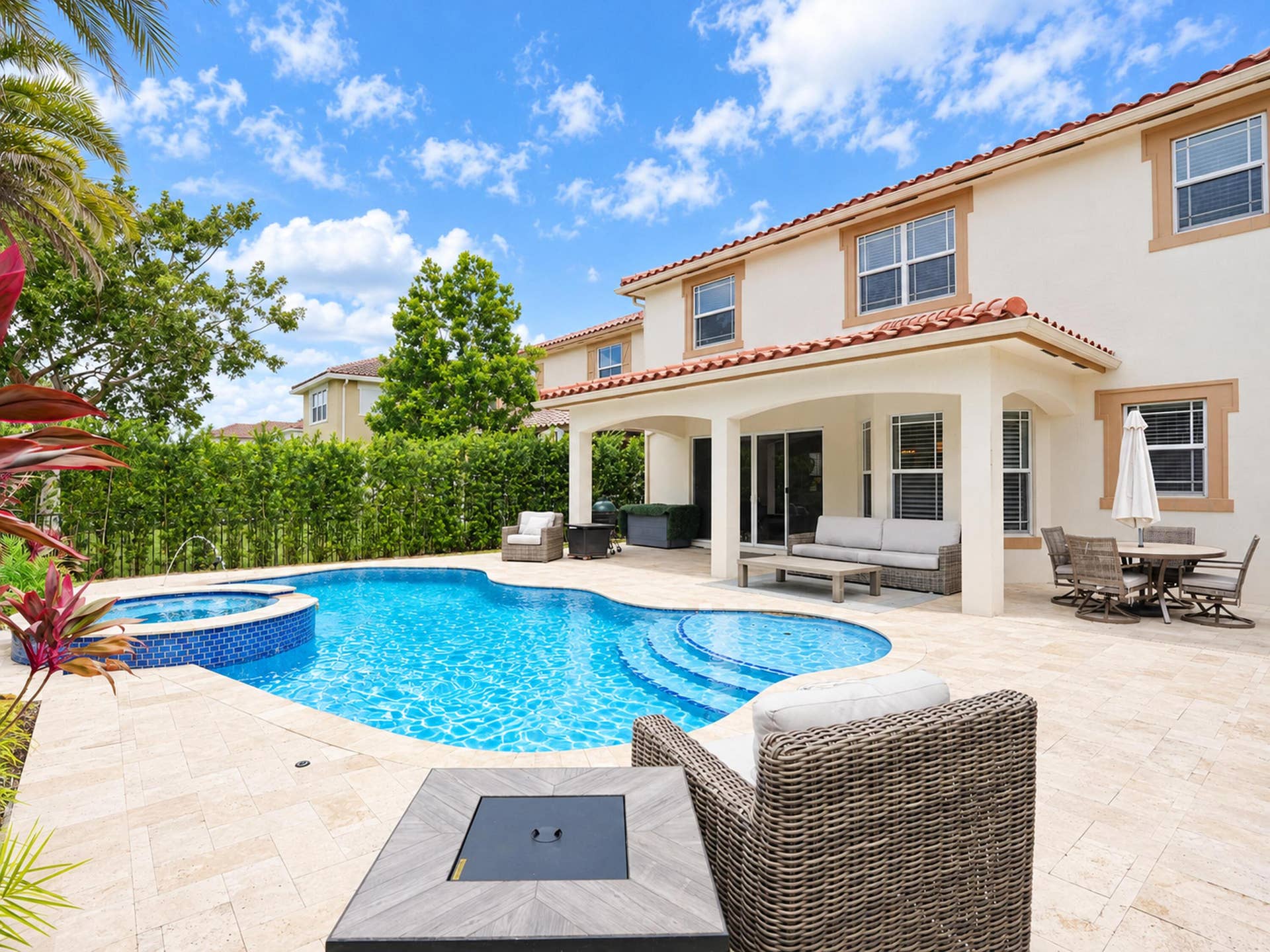 8601 Waterside Court, Parkland, FL 33076 Exterior stucco residence featuring a tile roof, covered patio, stone paver decking, and a pool with an integrated spa