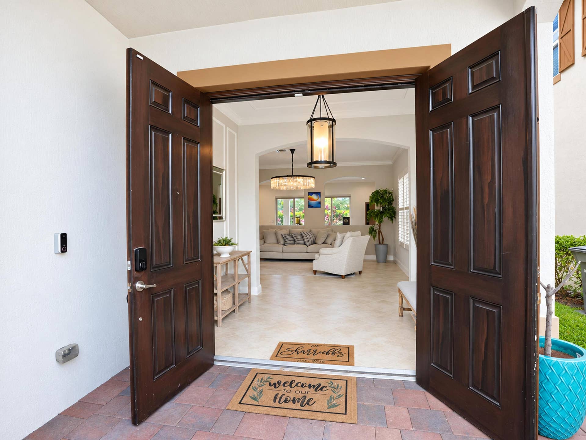 8601 Waterside Court, Parkland, FL 33076 Double entry door featuring dark wood-finish paneled doors and stone-paver flooring at the threshold, complemented by a hanging pendant light fixture and arched entryway