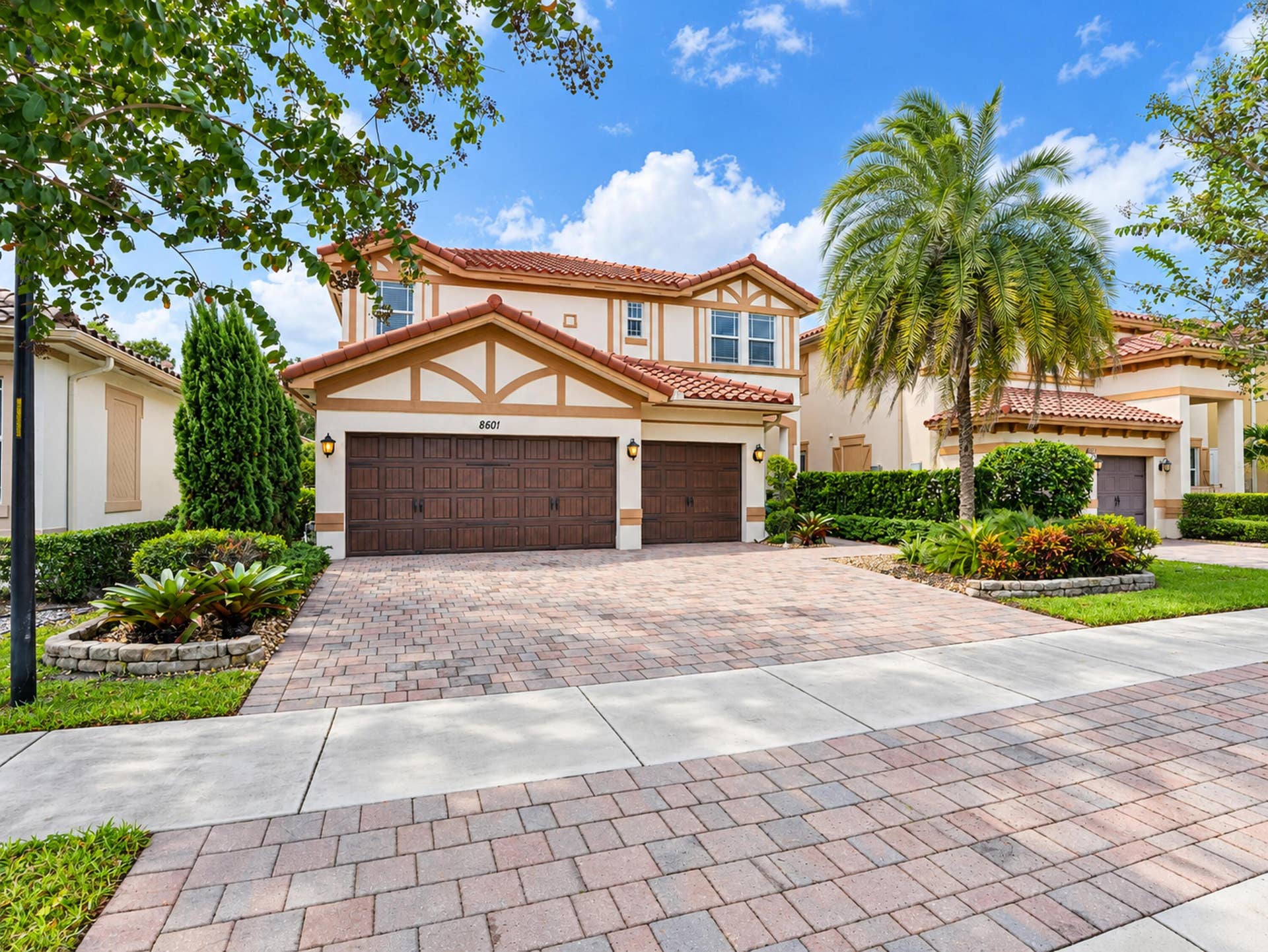8601 Waterside Court, Parkland, FL 33076 Two-story exterior featuring a tile roof, stucco finish, timber-frame detailing, and a multi-car garage with a paved driveway