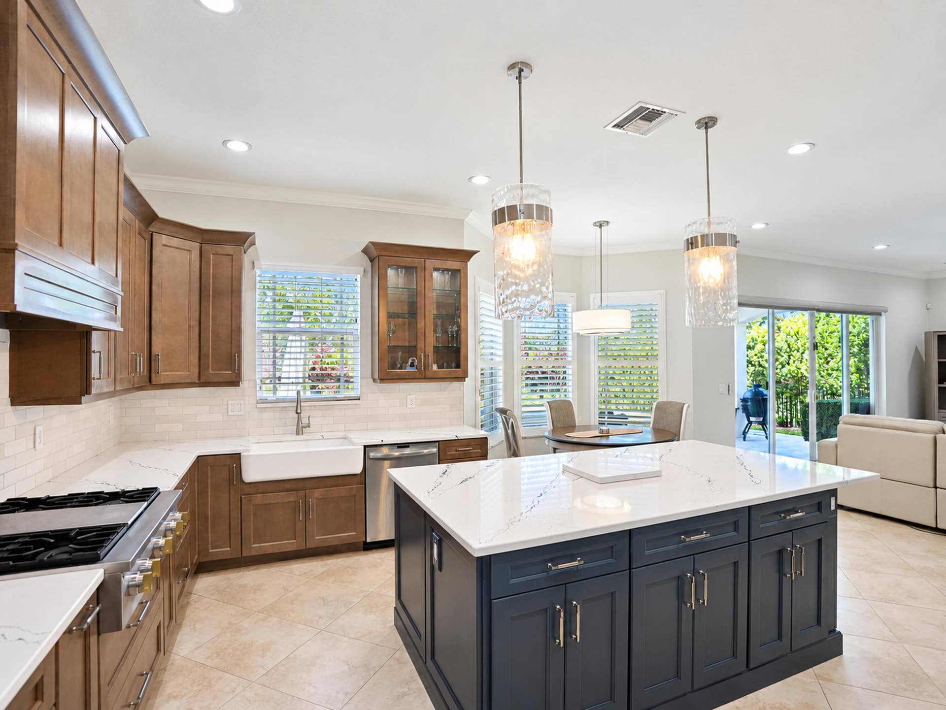 8601 Waterside Court, Parkland, FL 33076 Kitchen featuring a dual-tone cabinet design, quartz countertops, a porcelain farmhouse sink, stainless steel appliances, and a large center island