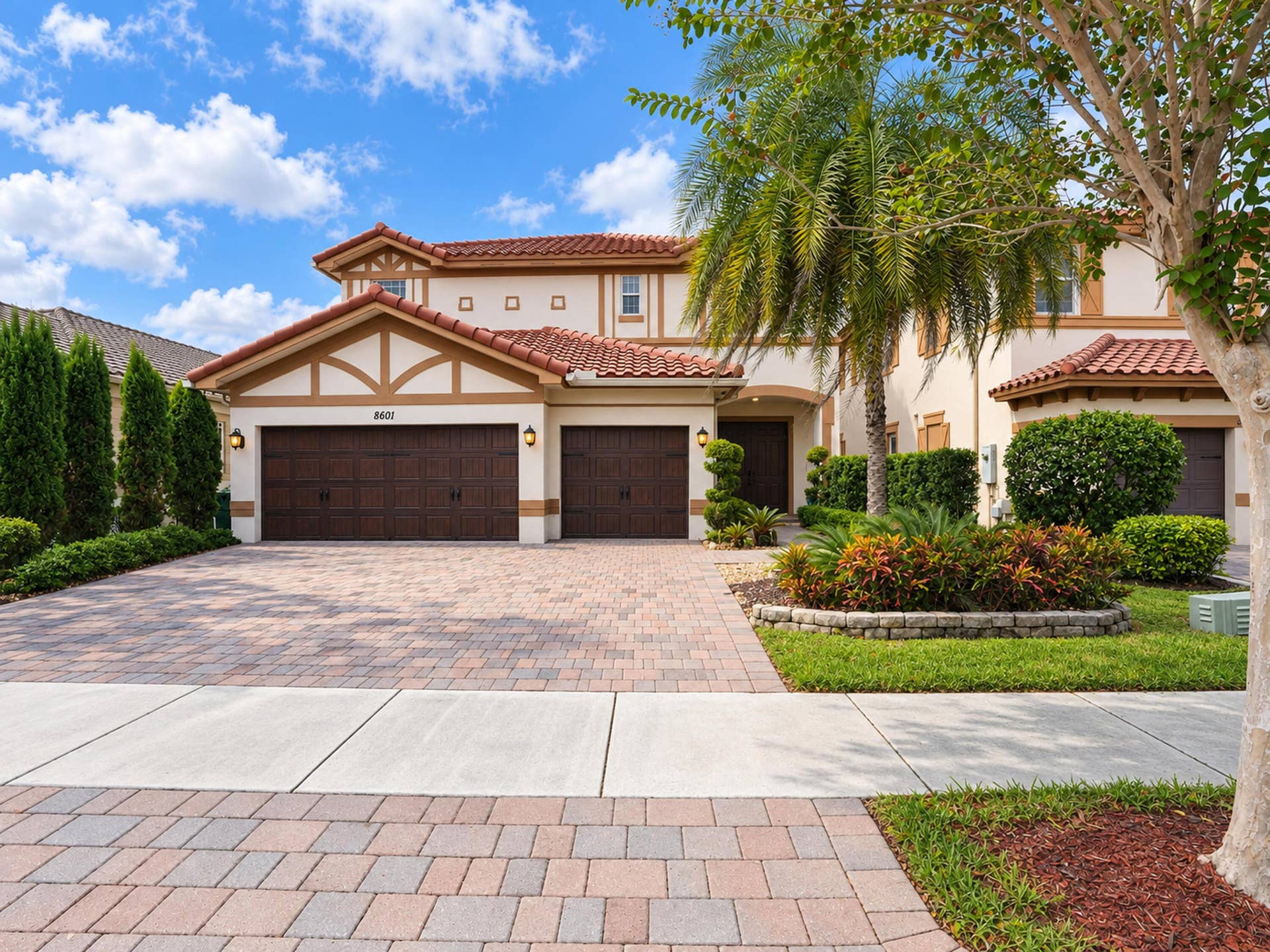 8601 Waterside Court, Parkland, FL 33076 Stucco exterior featuring a clay tile roof, three-car garage, and paver driveway with integrated landscaping