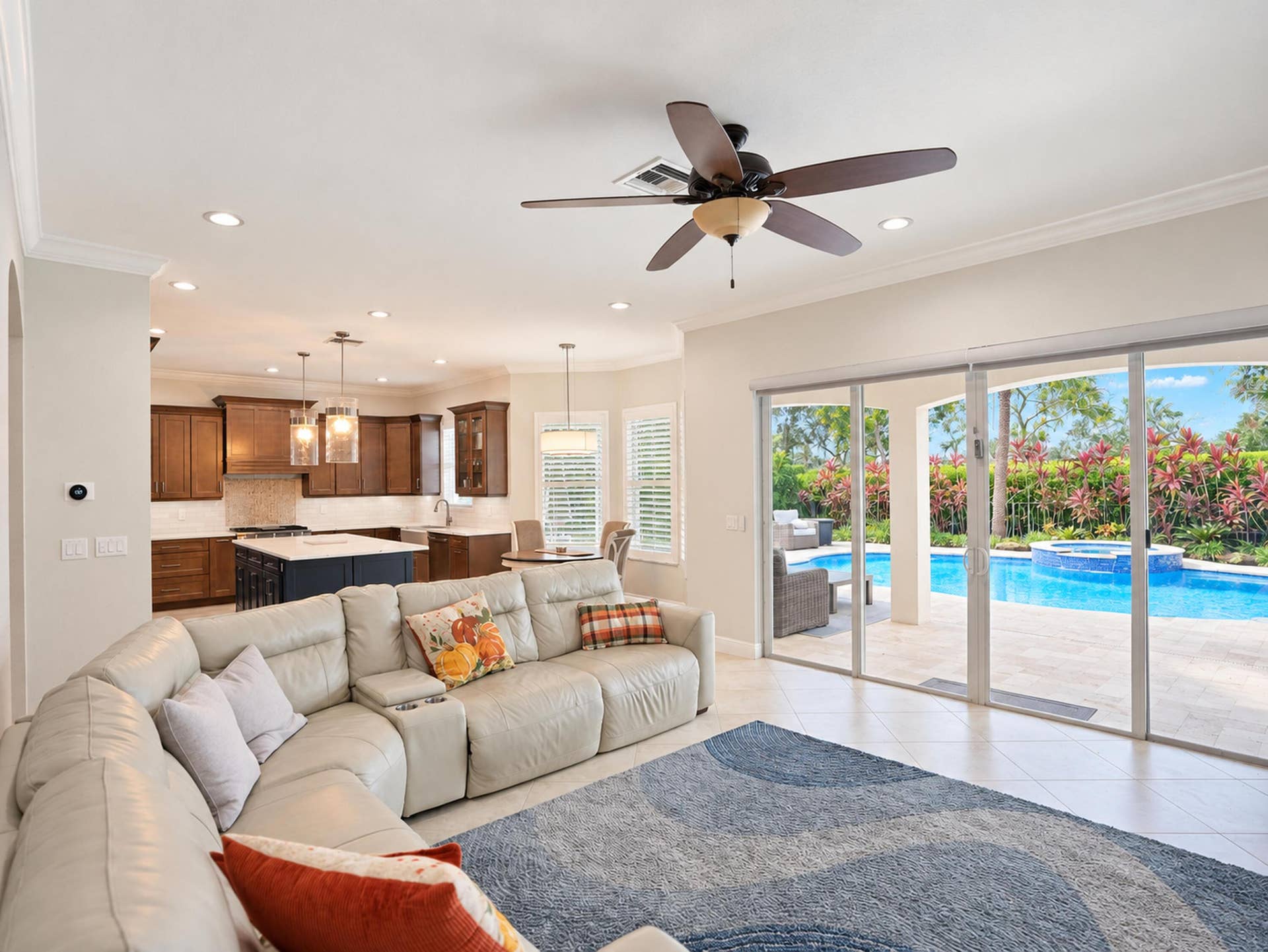 8601 Waterside Court, Parkland, FL 33076 Open-concept living space featuring wood-finish cabinetry, center kitchen island, recessed lighting, and large sliding glass doors opening to a private pool and patio area