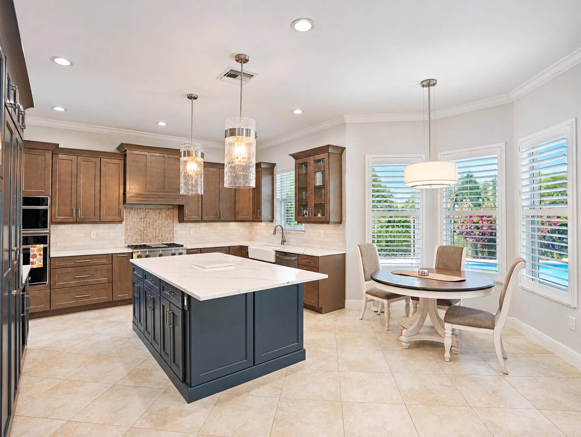 8601 Waterside Court, Parkland, FL 33076 Kitchen featuring custom wood cabinetry, central island with contrasting finish and stone-composite countertop, farmhouse sink, integrated double wall ovens, and recessed lighting